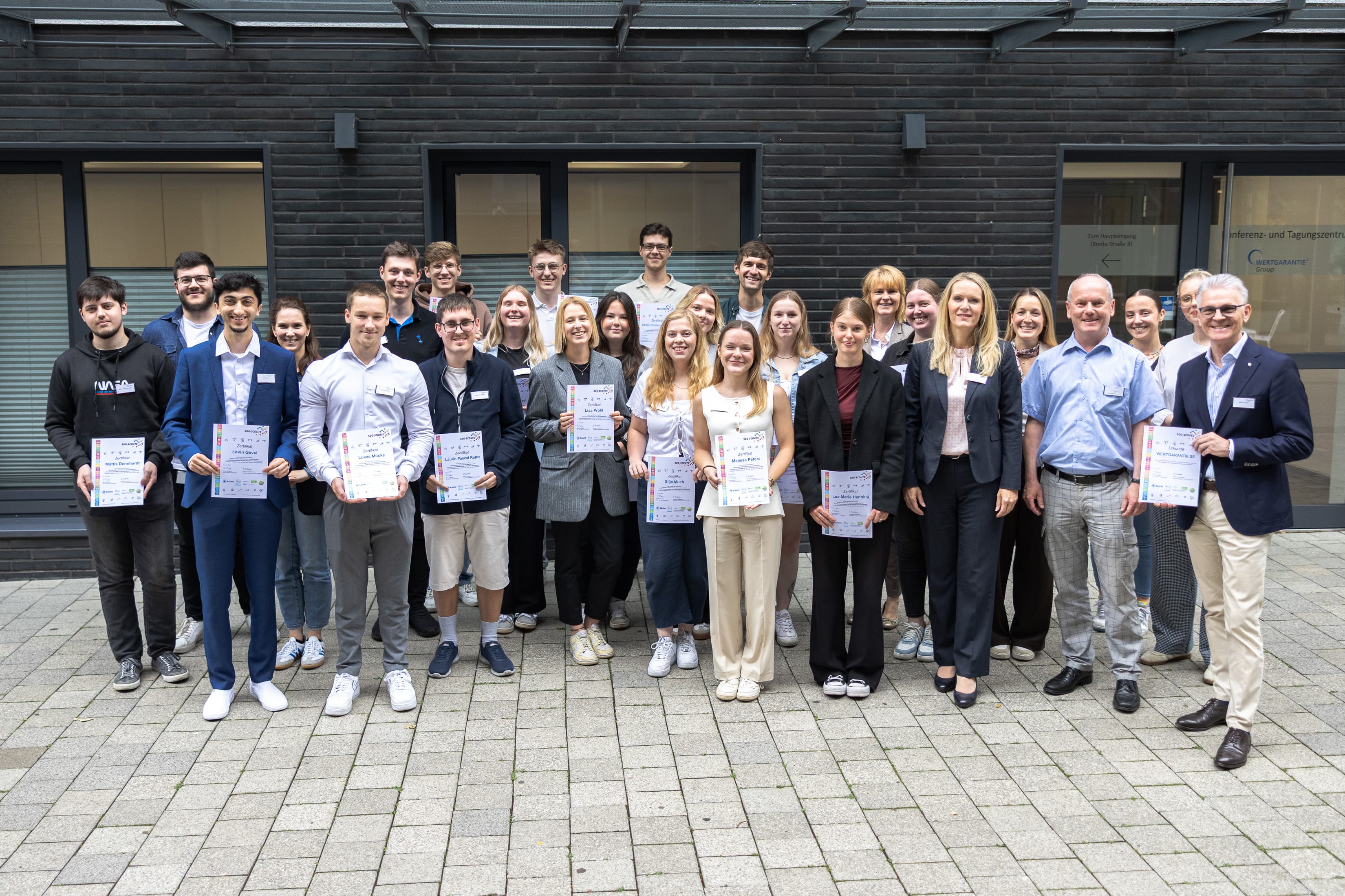 Die Young Talents der WERTGARANTIE Group halten stolz ihre Zertifkate für ihre SDG-Scout-Ausbildung in der Hand.