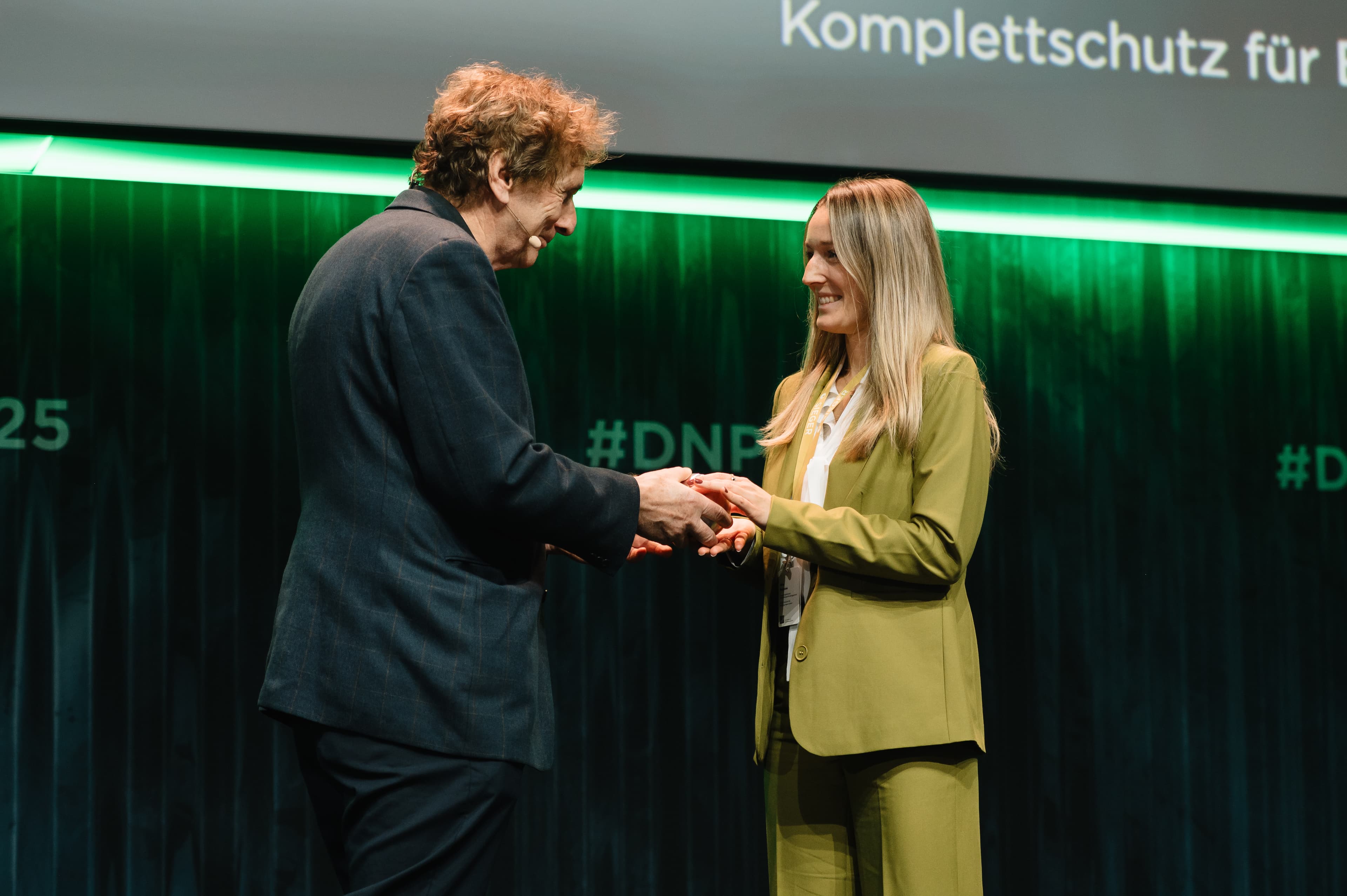 Der Abteilungsleiterin Nachhaltigkeitsmanagement Nina Ruhnow wird auf der Bühne der Deutsche Nachhaltigkeitspreis überreicht.