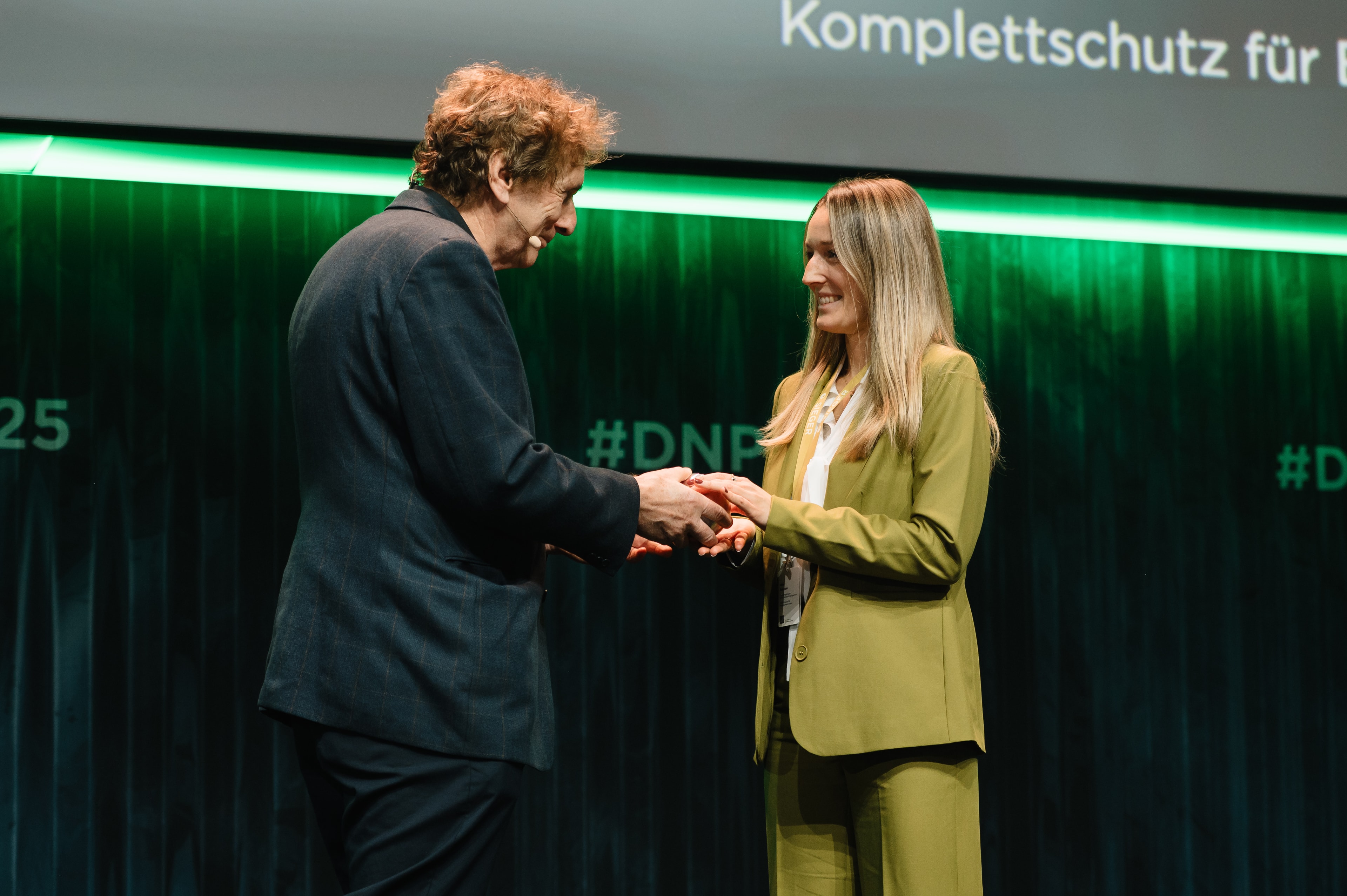 Der Abteilungsleiterin Nachhaltigkeitsmanagement Nina Ruhnow wird auf der Bühne der Deutsche Nachhaltigkeitspreis überreicht.
