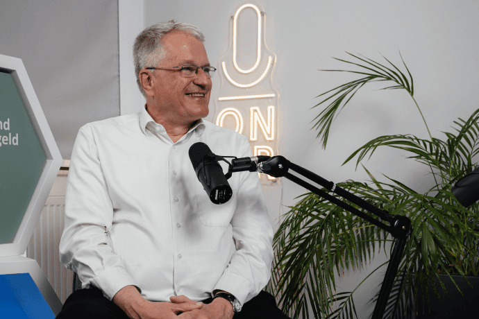 Folge 1 mit Oliver IT-Bereichleiter Oliver Simon sitzt in unserem Podcaststudio. Vor ihm ist ein Mikrofon aufgebaut.