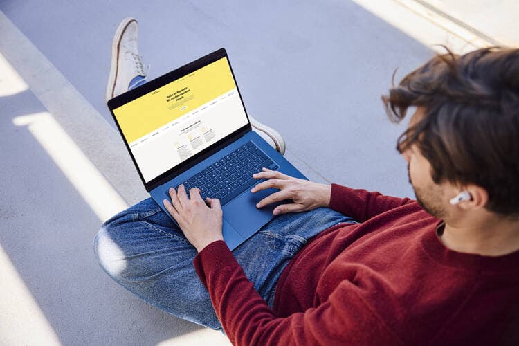 Recht auf Reparatur Ein Mann sitzt vor einem Laptop, auf dem eine gelbe Website zu sehen ist.